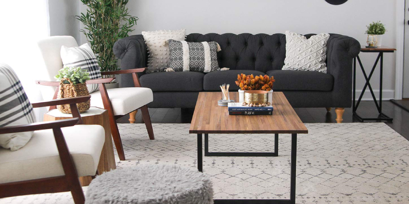 A Simple Living Room With Black Sofa And Chairs.